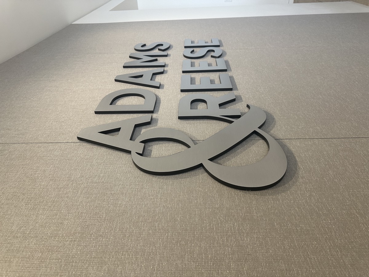 Brushed metal lobby letters stud-mounted on fabric wall panels, Houston TX — Adams & Reese